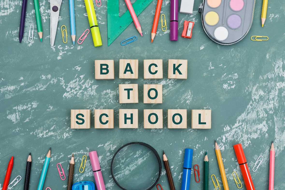 Back to school concept with wooden cubes, magnifying glass, school supplies on plaster background flat lay. 